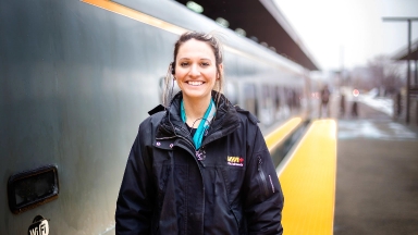 Employée souriante de VIA Rail devant un train